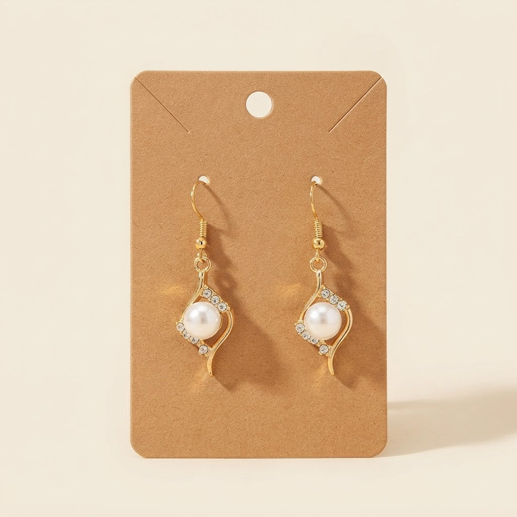 Boucles d’oreilles dorées perle et strass sur fond studio