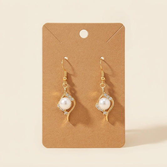 Boucles d’oreilles dorées perle et strass sur fond studio