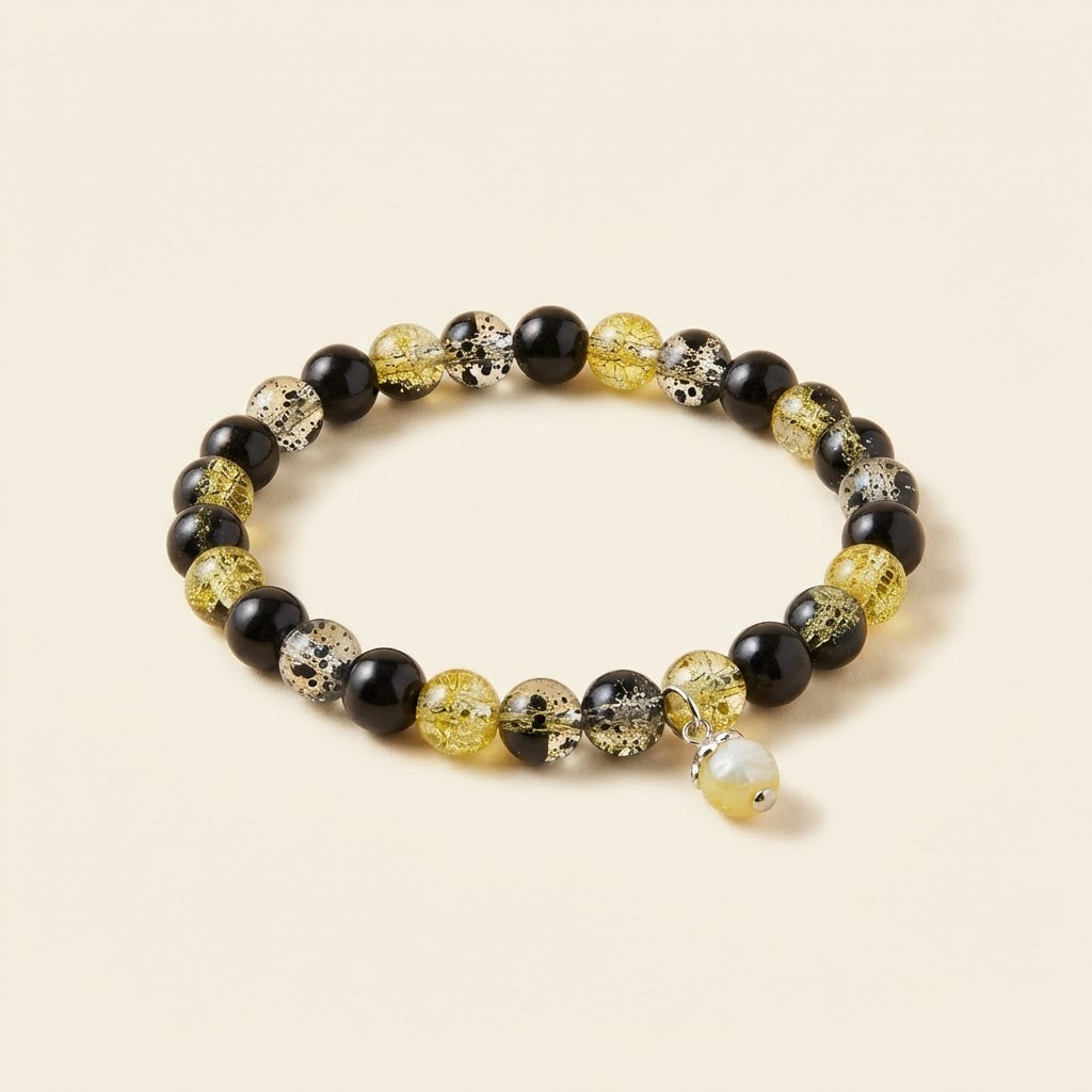 Bracelet noir et doré à breloque sur fond studio