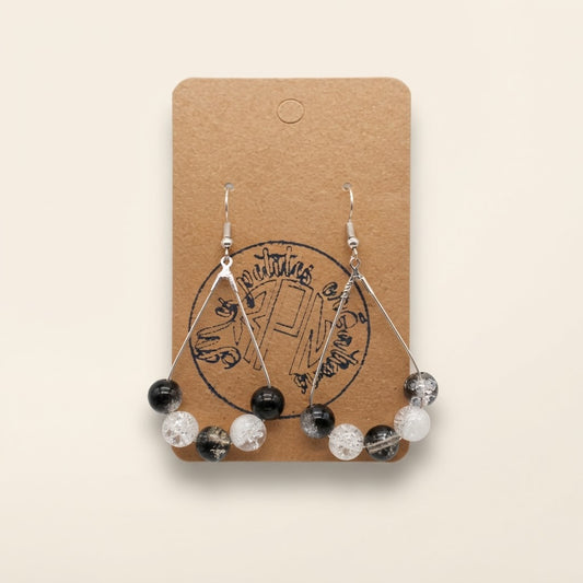 Boucles d’oreilles créoles noir blanc et cristal sur fond studio