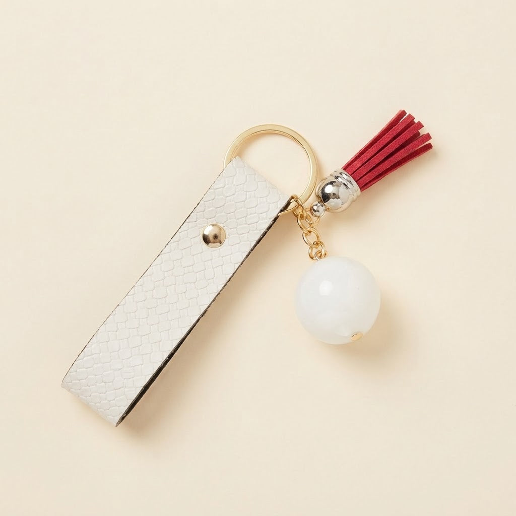 Porte-clés blanc avec pompon rouge sur fond studio