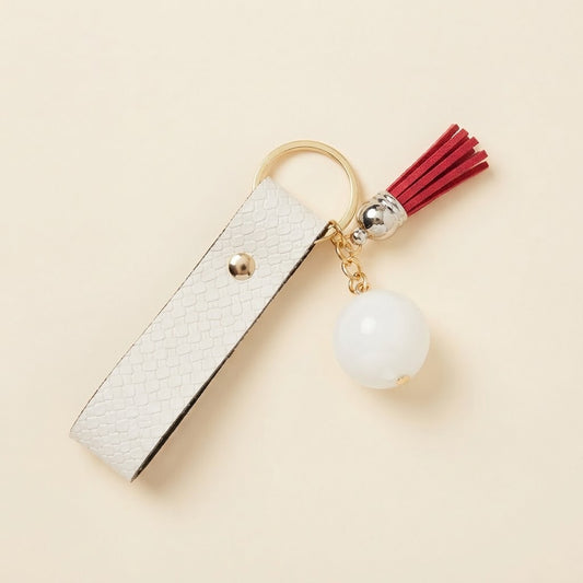 Porte-clés blanc avec pompon rouge sur fond studio