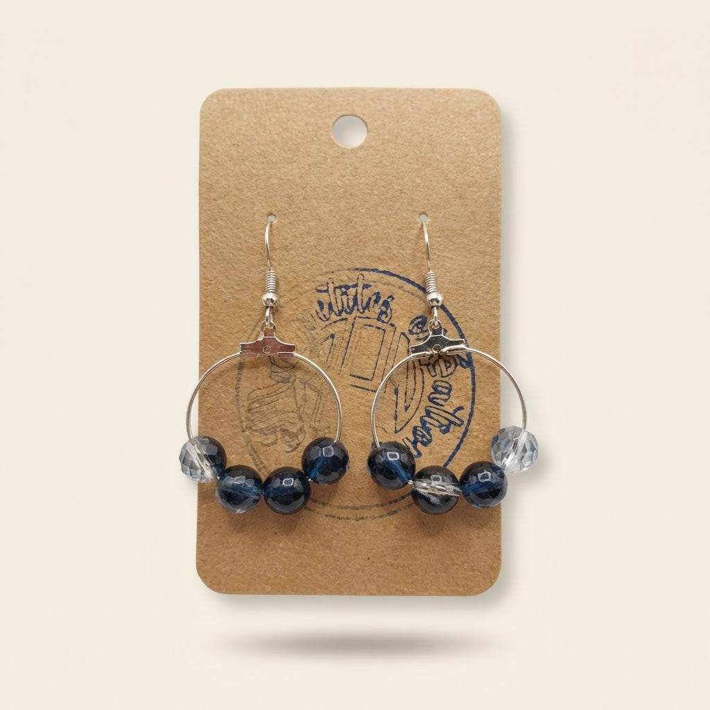 Boucles d’oreilles créoles bleu nuit et cristal sur fond studio